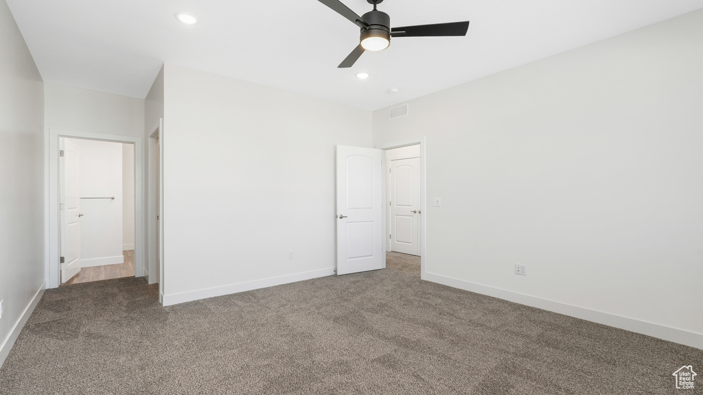 Unfurnished bedroom with ceiling fan and dark colored carpet