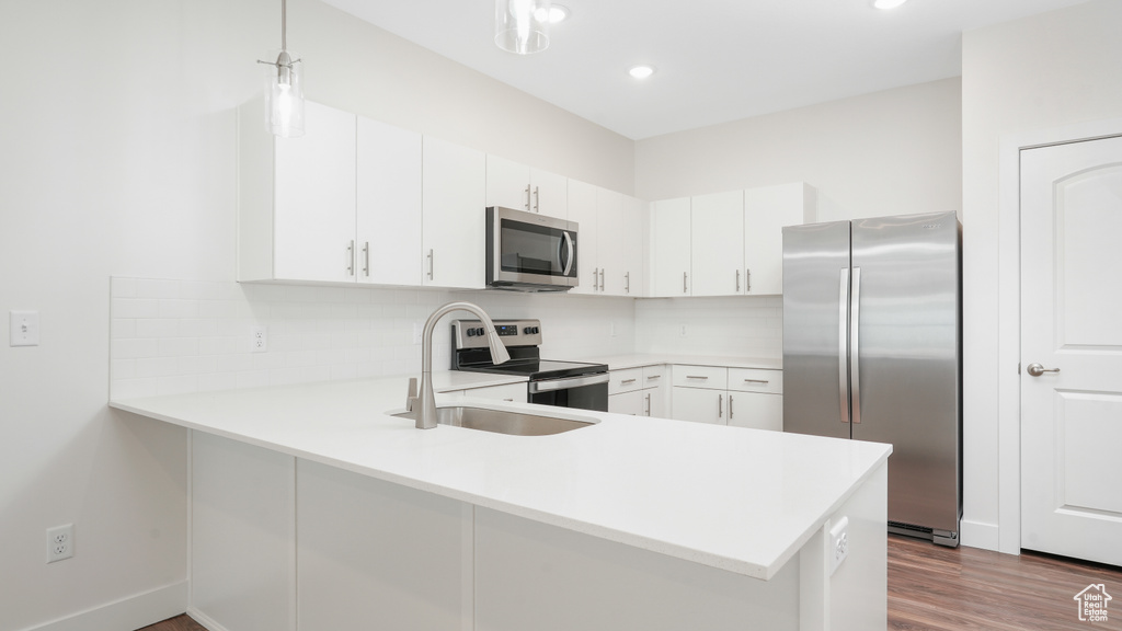 Kitchen featuring backsplash, stainless steel appliances, white cabinets, sink, and dark hardwood / wood-style flooring