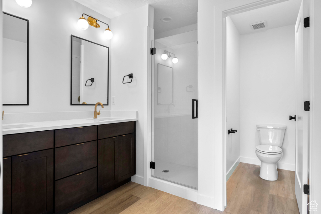 Bathroom featuring walk in shower, toilet, double sink vanity, and hardwood / wood-style floors