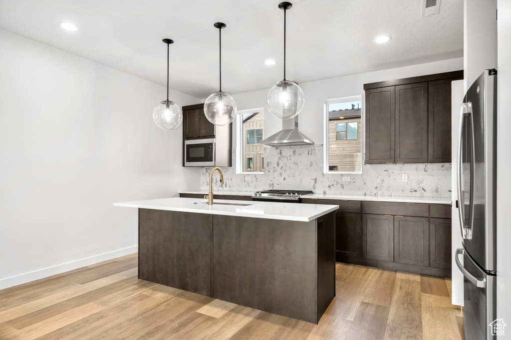 Kitchen with sink, tasteful backsplash, stainless steel appliances, and light hardwood / wood-style floors