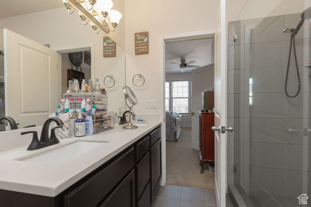 Bathroom with walk in shower, ceiling fan with notable chandelier, large vanity, and tile floors