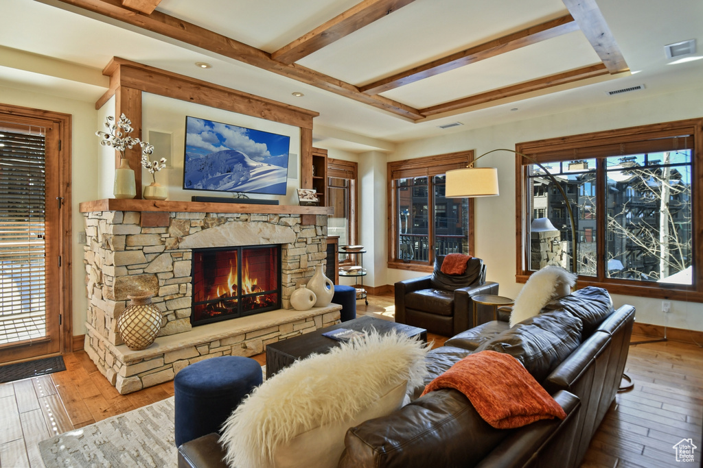 Living room with a fireplace, light hardwood / wood-style flooring, and beam ceiling
