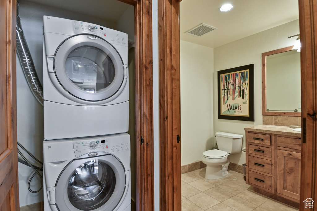 Laundry room with light tile floors and stacked washer and clothes dryer