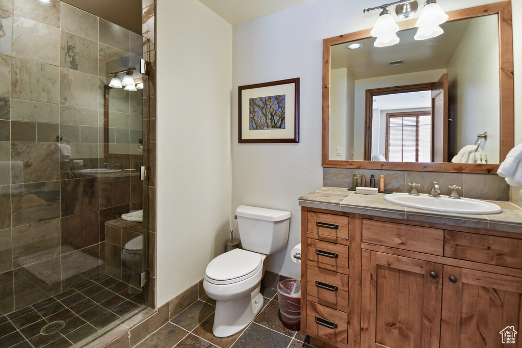 Bathroom featuring vanity, toilet, a shower with shower door, and tile floors