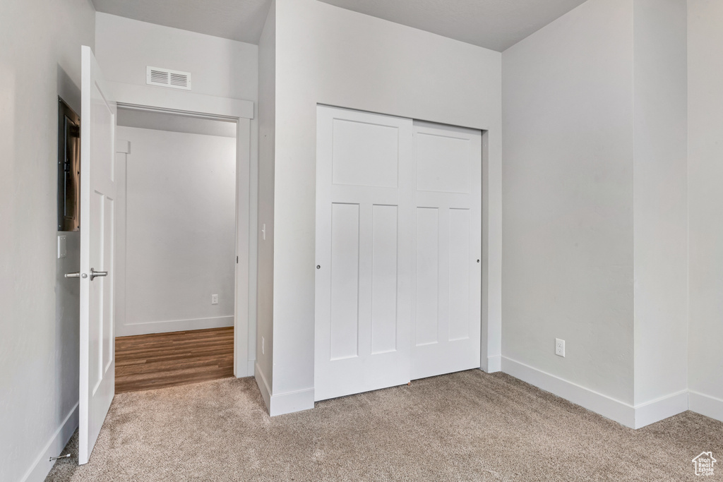 Unfurnished bedroom featuring light carpet and a closet