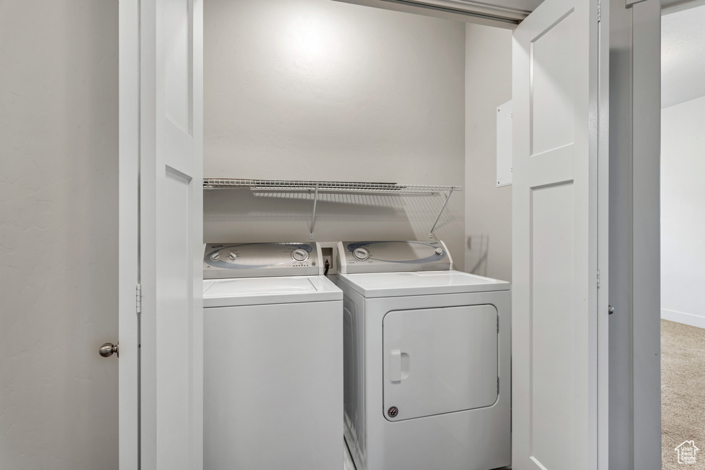 Laundry room with washer and clothes dryer and carpet flooring