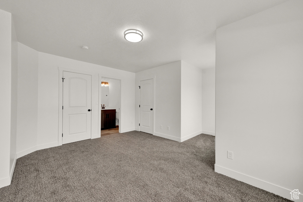 Interior space featuring ensuite bath and dark colored carpet