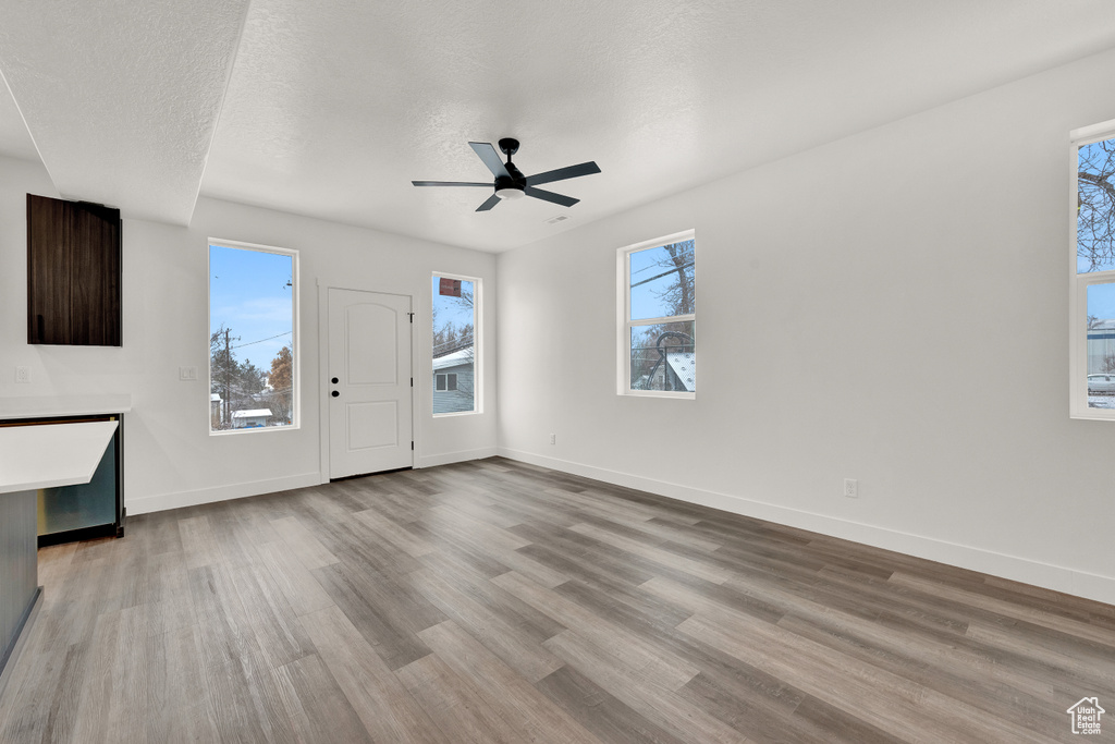 Unfurnished living room featuring a wealth of natural light, ceiling fan, and hardwood / wood-style floors