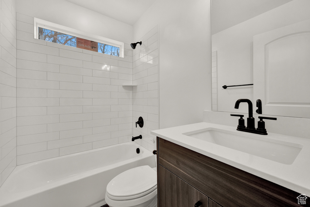 Full bathroom with vanity with extensive cabinet space, tiled shower / bath combo, and toilet