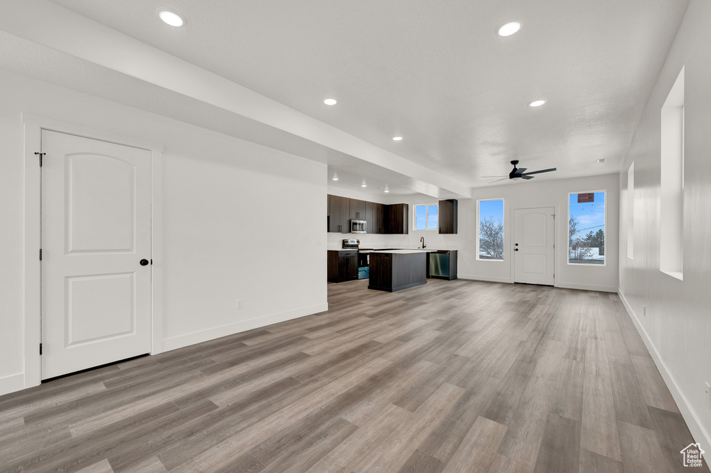 Unfurnished living room with light hardwood / wood-style floors, sink, and ceiling fan