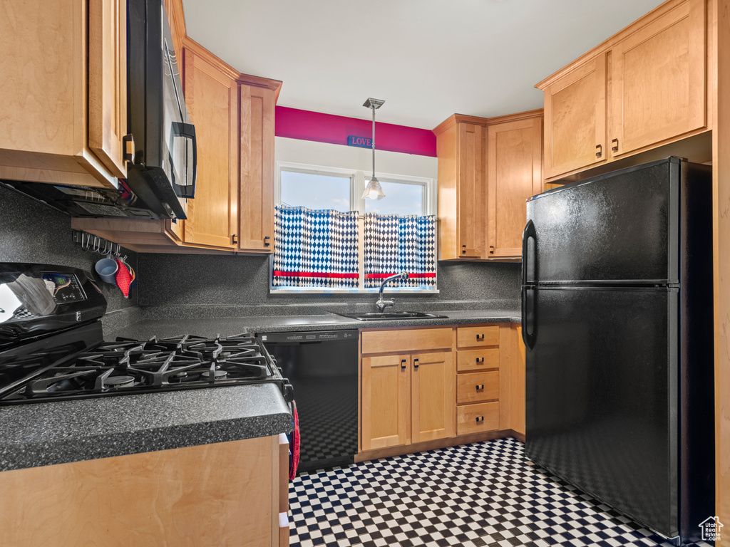 Kitchen with pendant lighting, black appliances, sink, and backsplash
