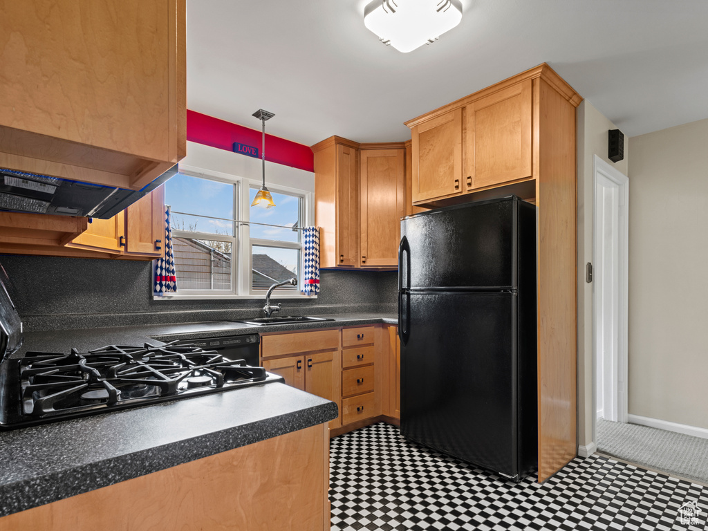 Kitchen featuring black refrigerator, sink, hanging light fixtures, and tasteful backsplash