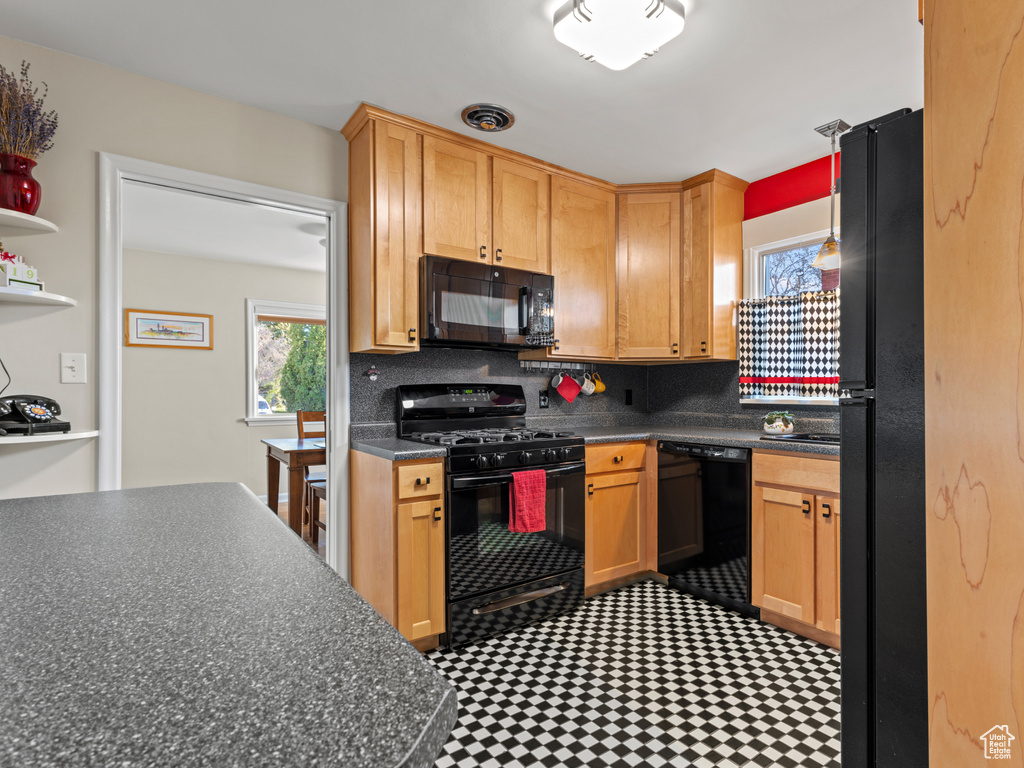 Kitchen featuring dark tile flooring, backsplash, and black appliances