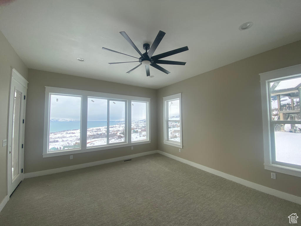 Carpeted empty room featuring ceiling fan and a water view