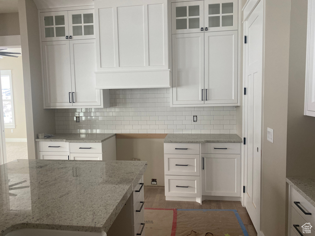 Kitchen featuring white cabinetry, tasteful backsplash, and light stone counters