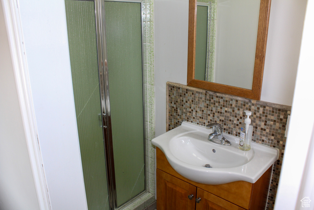 Bathroom featuring backsplash, oversized vanity, and a shower with shower door