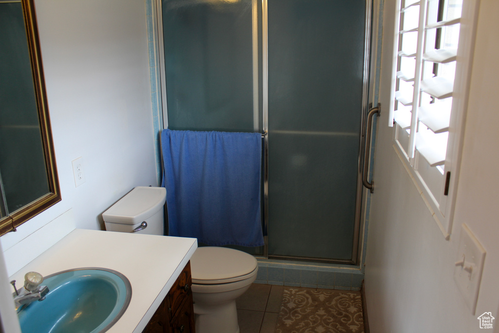 Bathroom featuring tile flooring, a shower with shower door, vanity, and toilet