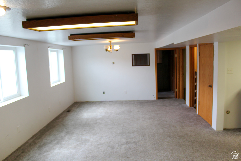 Basement with light colored carpet and a chandelier