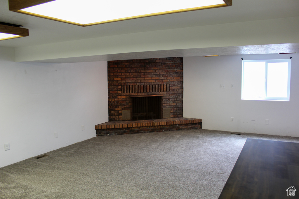 Unfurnished living room with a brick fireplace, carpet, and brick wall