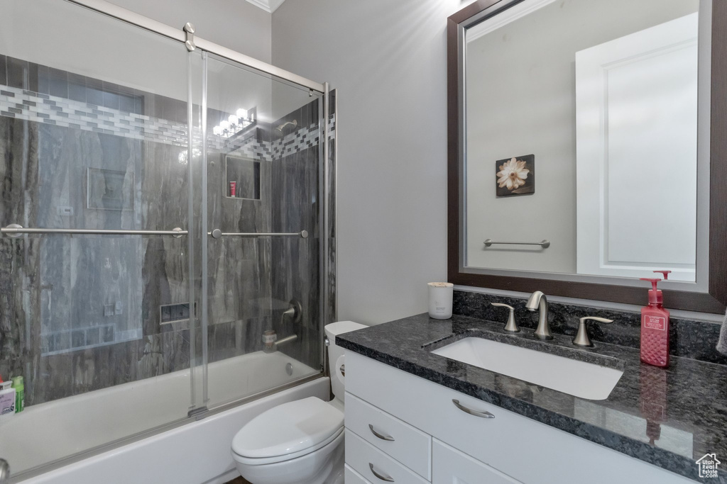 Full bathroom with toilet, large vanity, and shower / bath combination with glass door