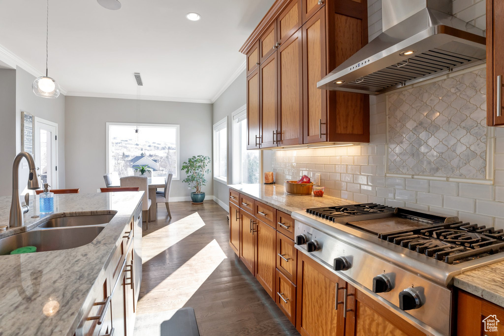Kitchen with tasteful backsplash, dark hardwood / wood-style flooring, sink, pendant lighting, and wall chimney exhaust hood