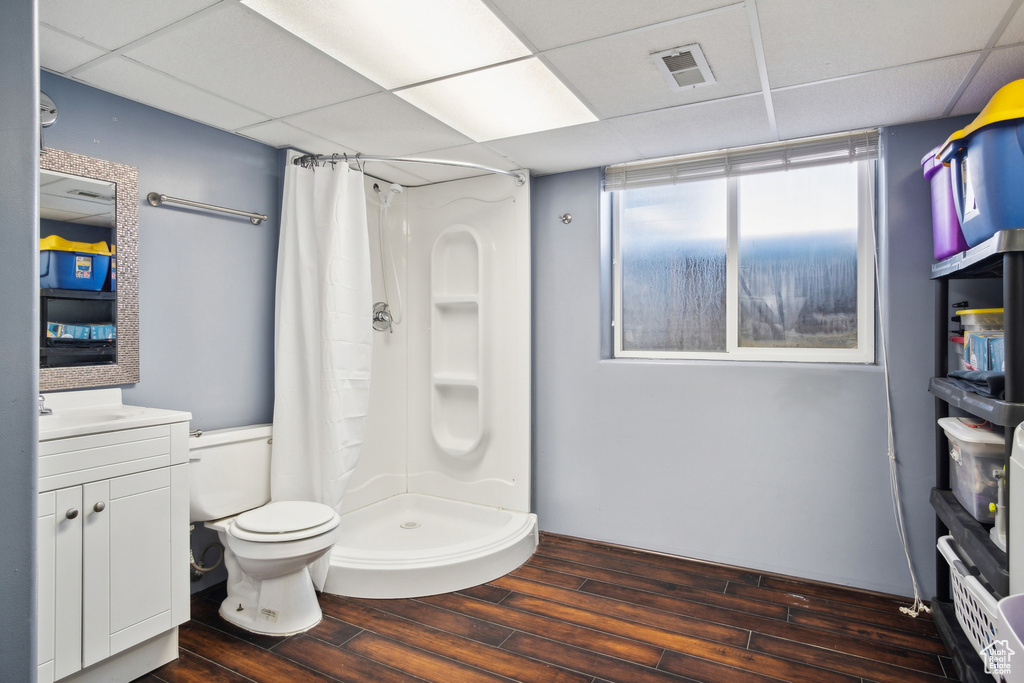 Bathroom featuring hardwood / wood-style floors, a paneled ceiling, curtained shower, toilet, and vanity with extensive cabinet space