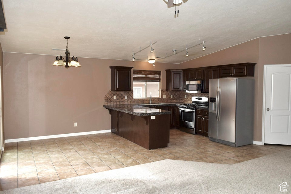 Kitchen featuring appliances with stainless steel finishes, a chandelier, kitchen peninsula, and light carpet