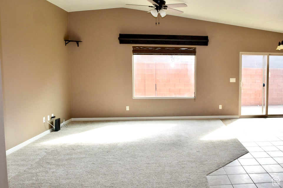 Spare room with vaulted ceiling, light tile floors, and ceiling fan