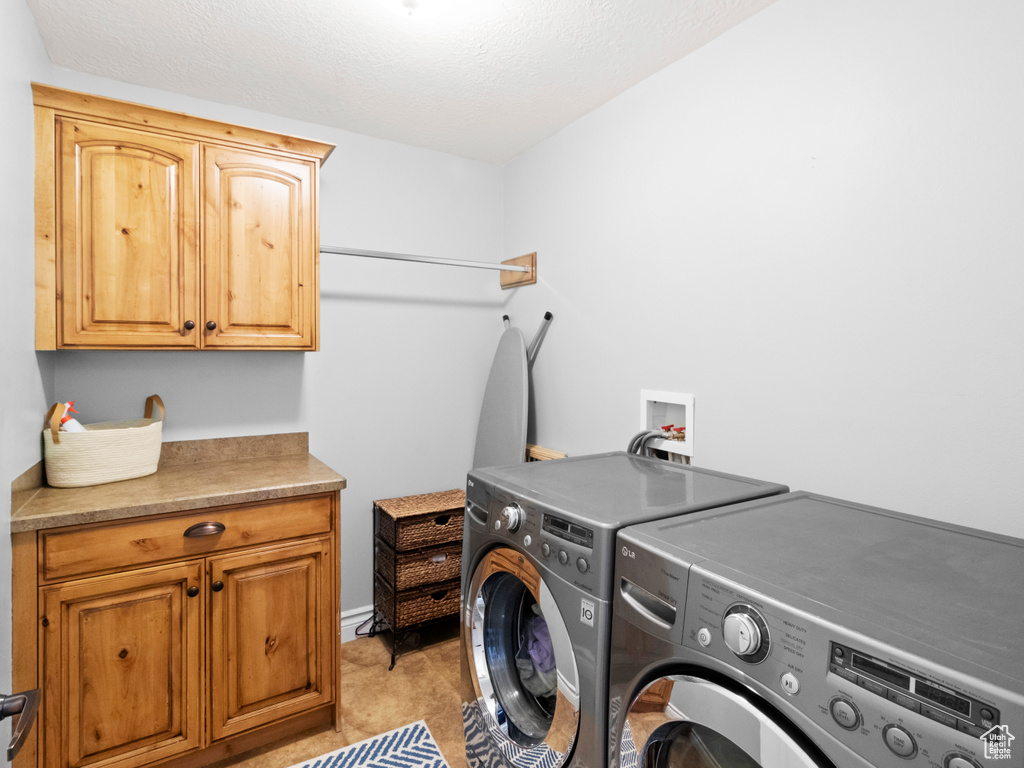 Laundry area with washing machine and dryer, cabinets, and washer hookup