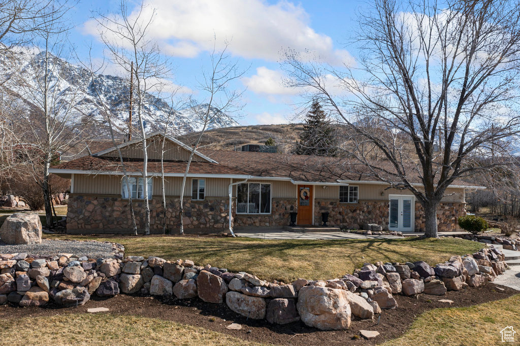 Single story home with a front yard, french doors, and a mountain view