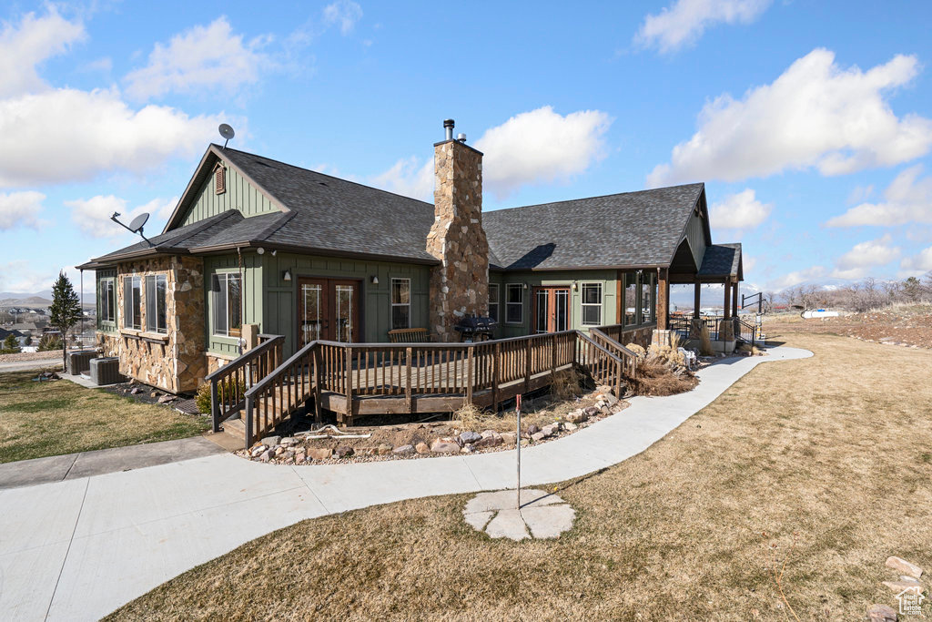 View of front of house with a front yard, french doors, central air condition unit, and a wooden deck