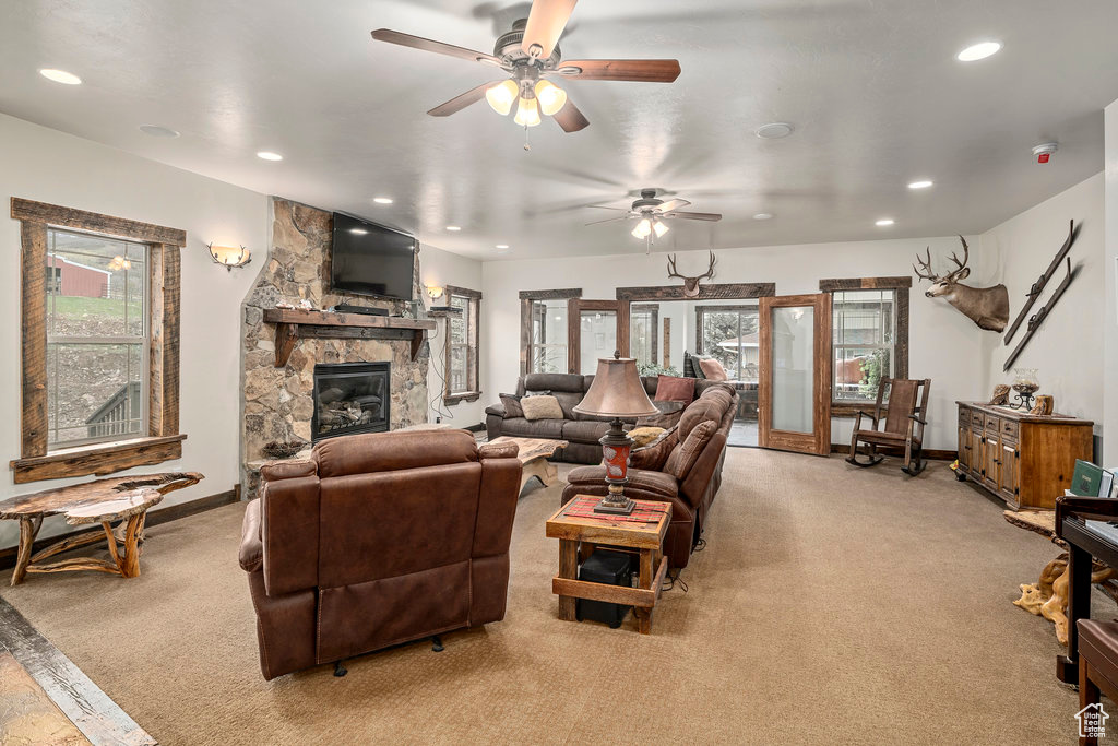 Living room with a fireplace, light carpet, plenty of natural light, and ceiling fan
