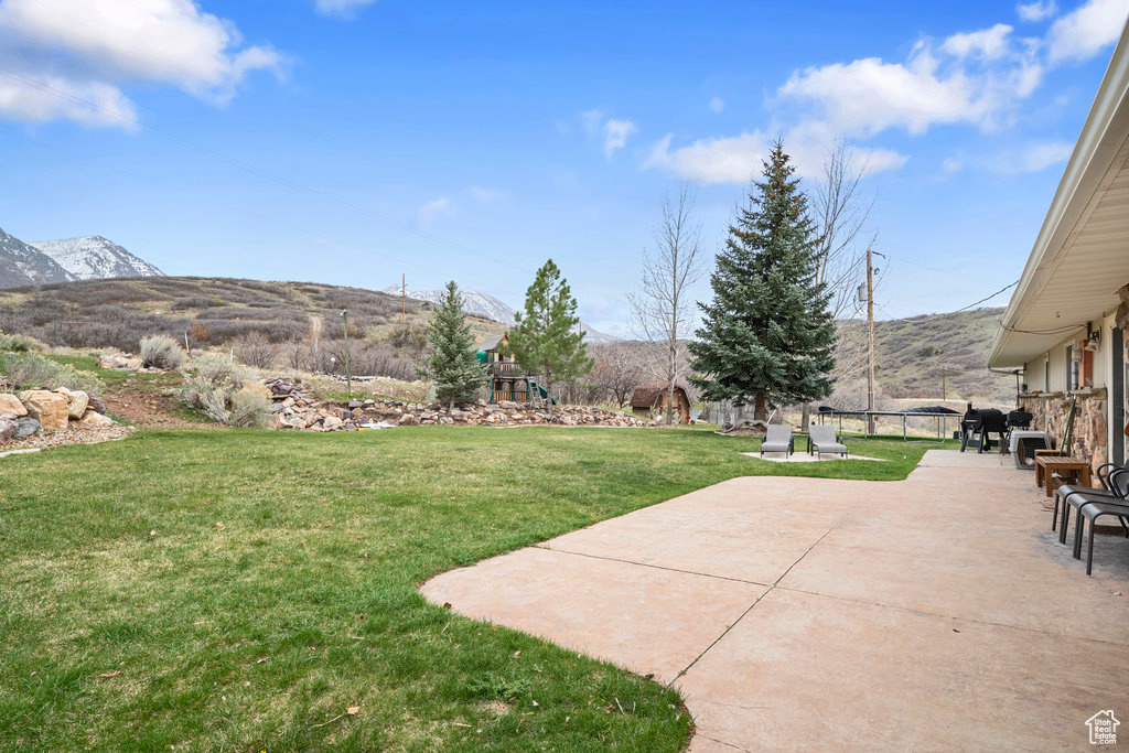 View of yard featuring a mountain view, a playground, and a patio