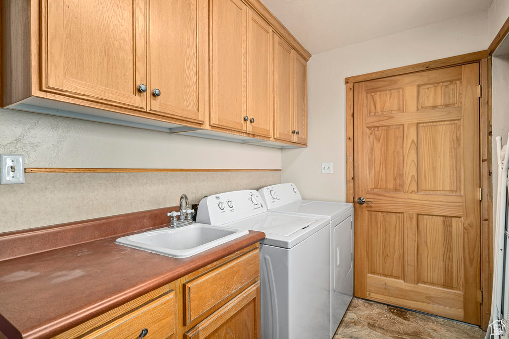 Laundry room featuring cabinets, washer and dryer, sink, and light tile floors