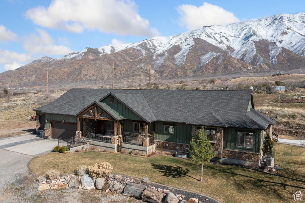 View of front of home featuring a front lawn, a garage, a mountain view, and covered porch