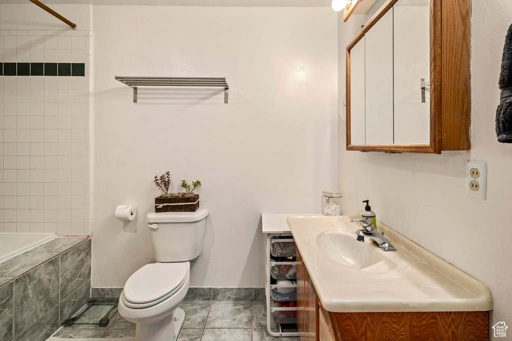 Full bathroom with vanity, toilet, tiled shower / bath combo, and tile floors