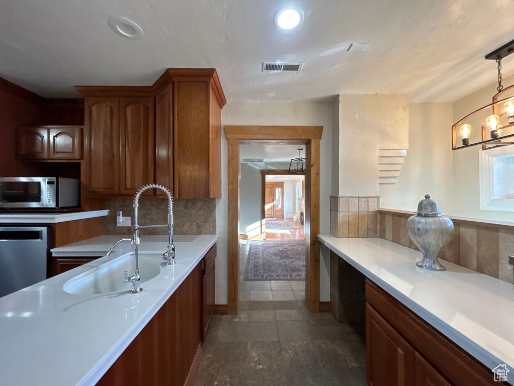 Kitchen featuring sink, appliances with stainless steel finishes, decorative light fixtures, a chandelier, and dark tile floors