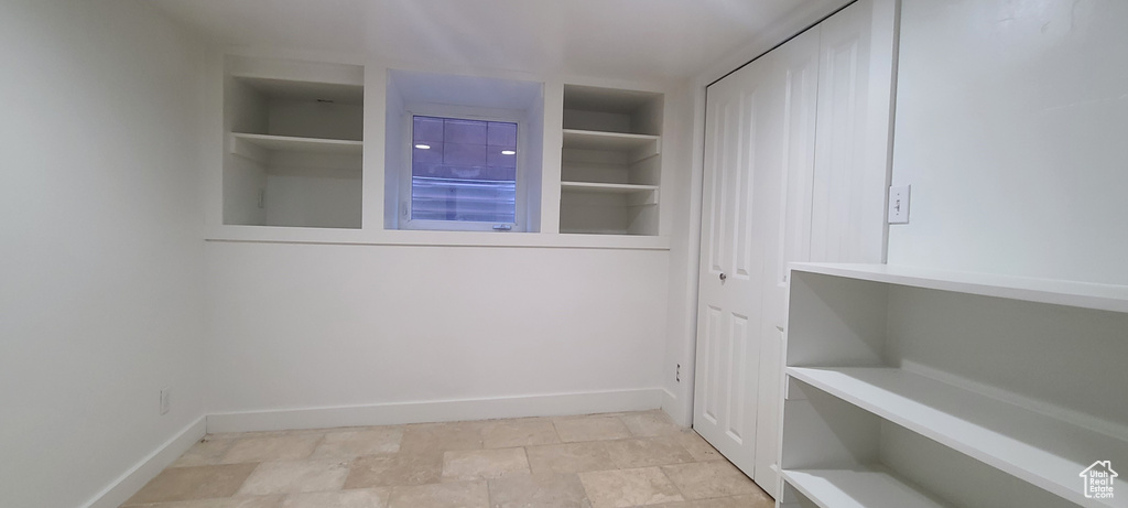 Laundry area with built in shelves and light tile floors
