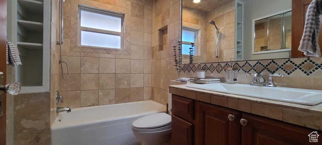Full bathroom featuring a wealth of natural light, vanity, toilet, and tiled shower / bath combo