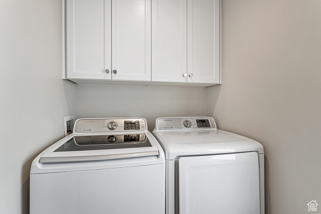 Washroom featuring washer hookup, washing machine and dryer, and cabinets