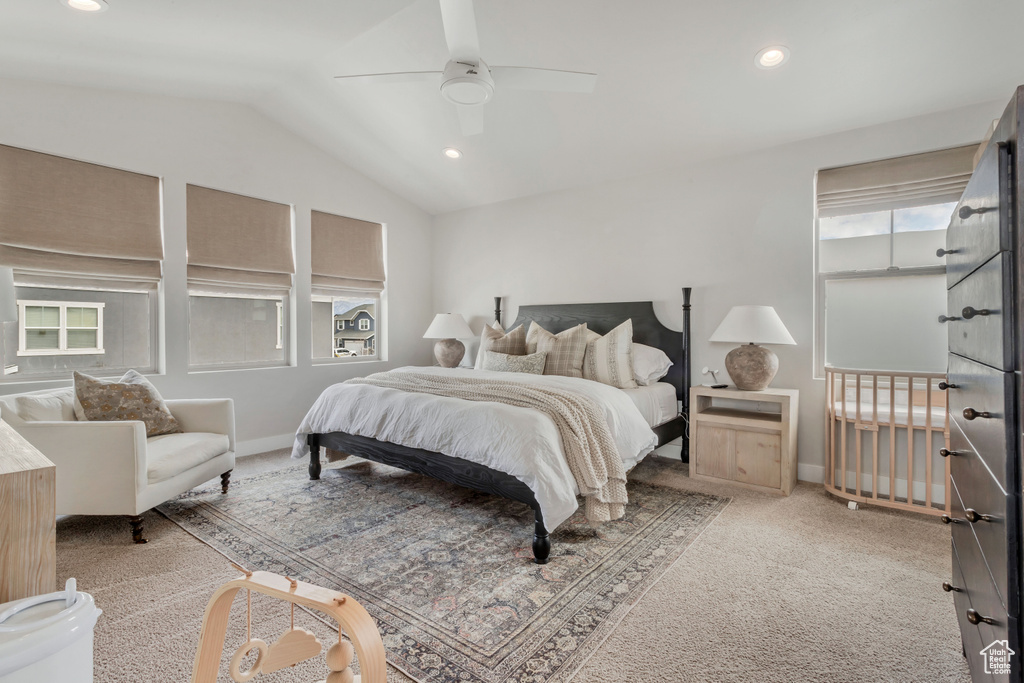 Carpeted bedroom featuring multiple windows, vaulted ceiling, and ceiling fan