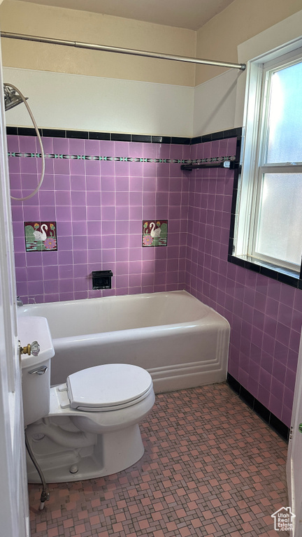 Bathroom featuring toilet, tiled shower / bath combo, and tile flooring