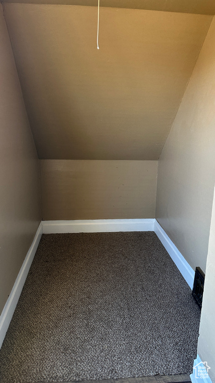 Additional living space with vaulted ceiling and carpet
