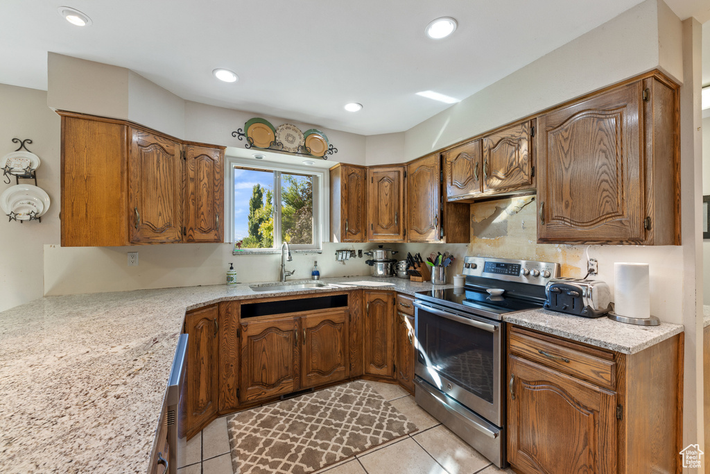 Kitchen with tasteful backsplash, light tile flooring, sink, electric range, and light stone countertops