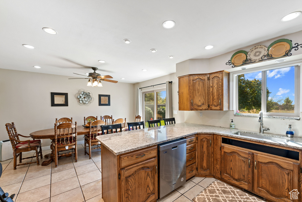 Kitchen with light tile floors, ceiling fan, dishwasher, sink, and light stone countertops