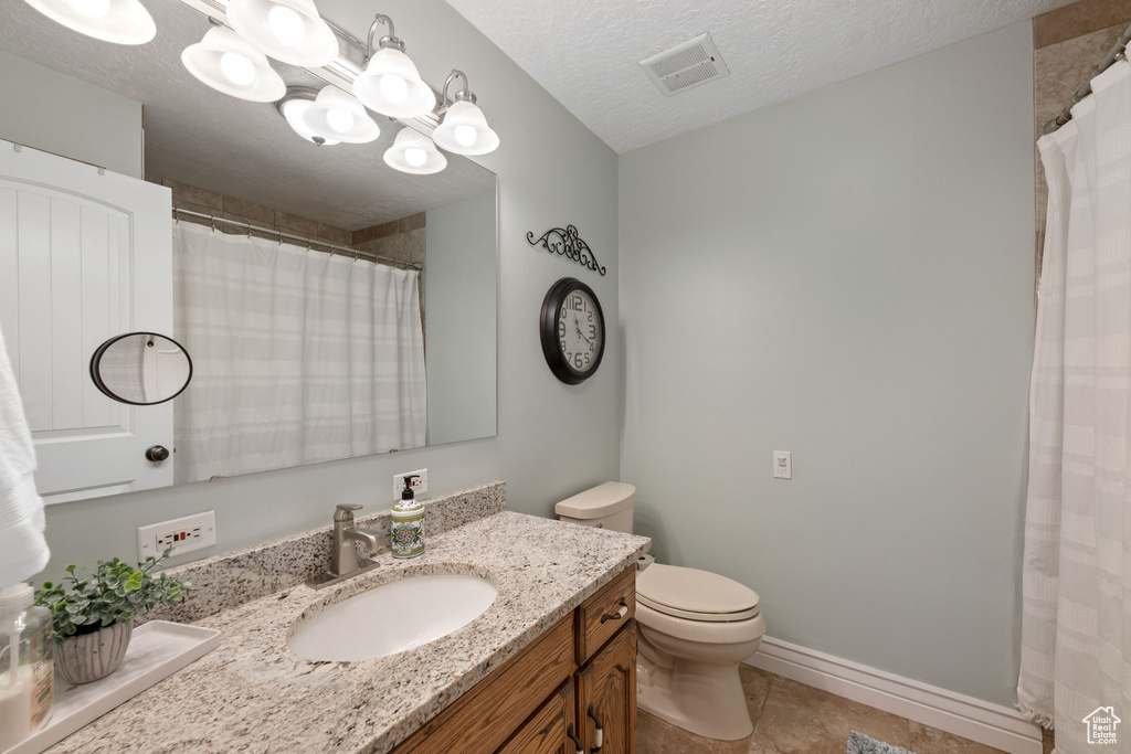 Bathroom featuring a notable chandelier, tile floors, a textured ceiling, toilet, and vanity
