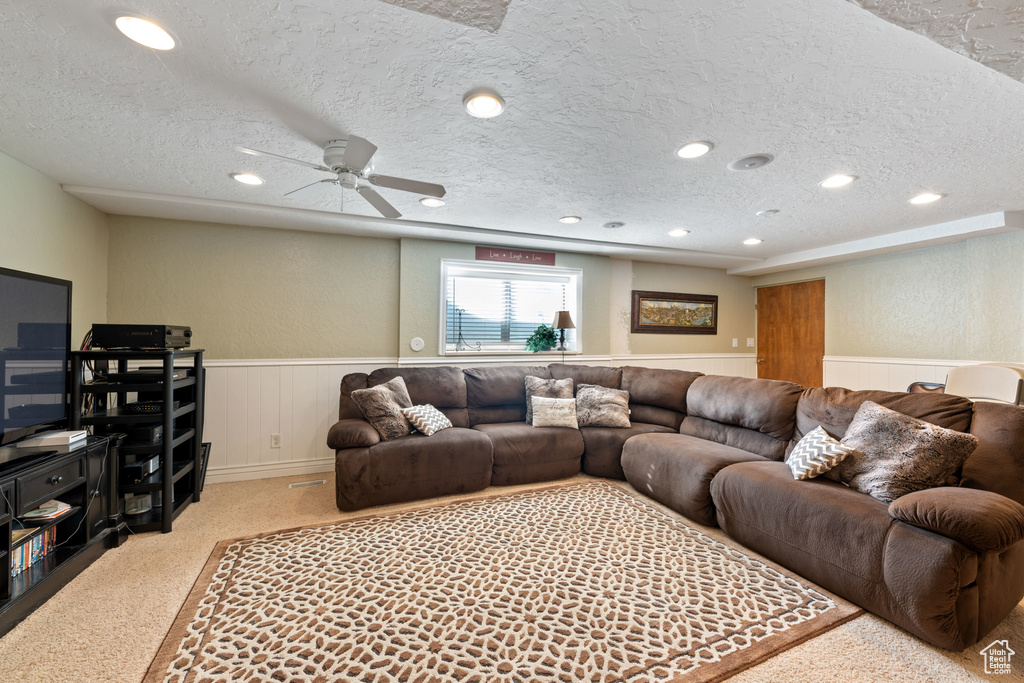 Living room featuring light colored carpet, a textured ceiling, and ceiling fan