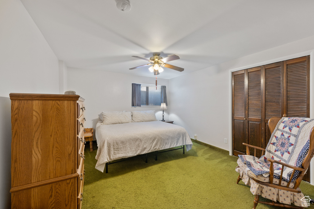 Carpeted bedroom with ceiling fan and a closet