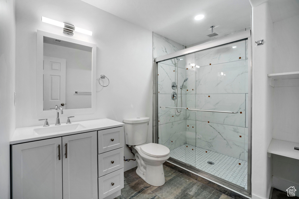 Bathroom with vanity, toilet, wood-type flooring, and a shower with door