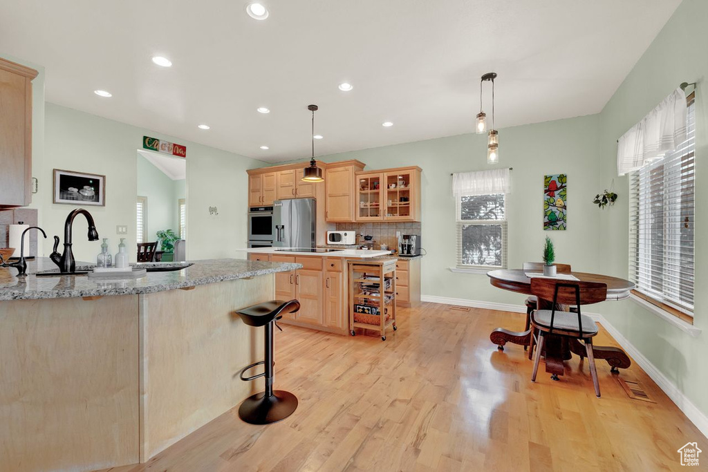Kitchen featuring a wealth of natural light, light brown cabinetry, light hardwood / wood-style floors, and backsplash